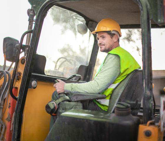 man using front end loader digging day light